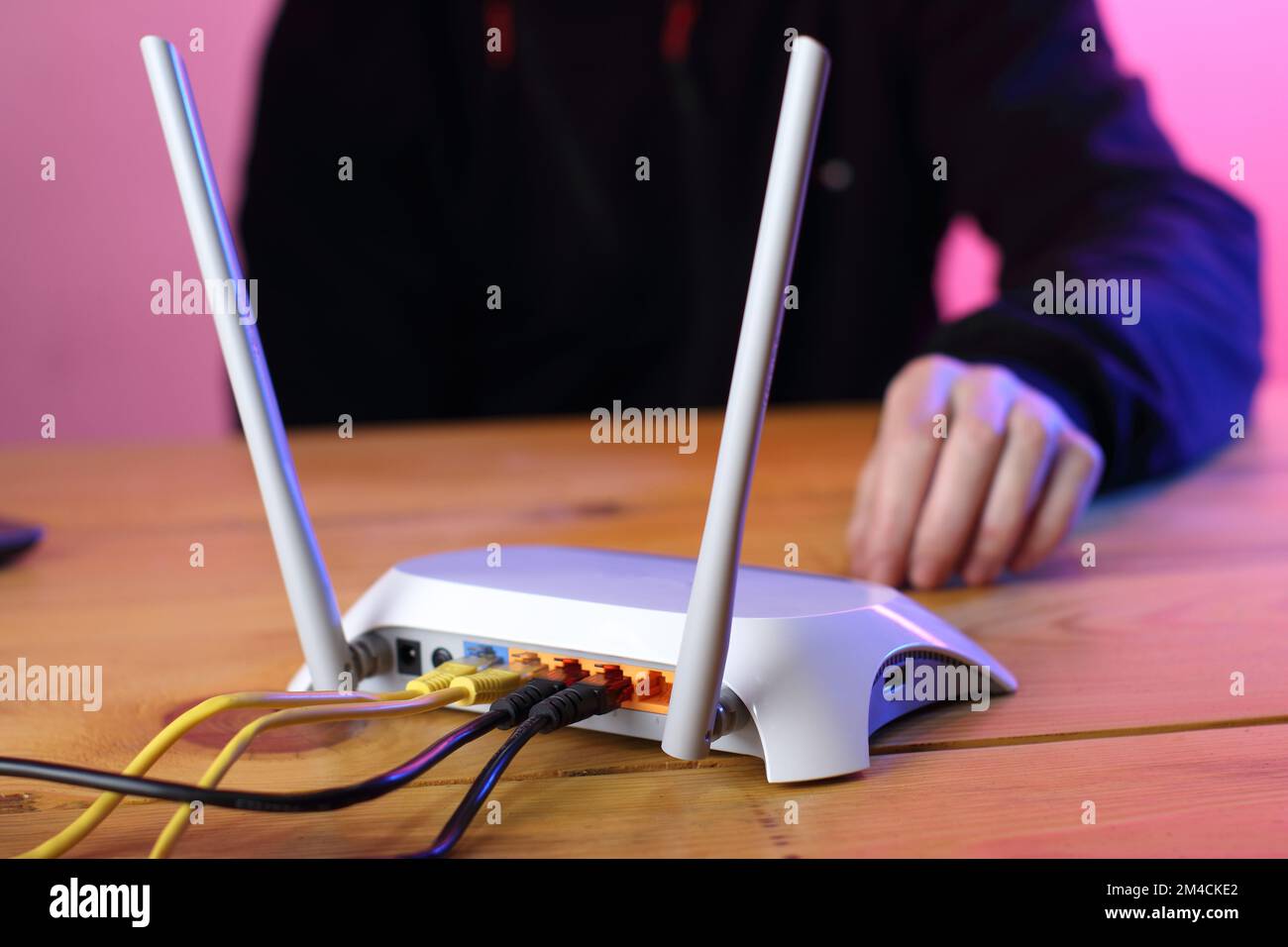 router with connected ethernet cables on table and colored background Stock Photo