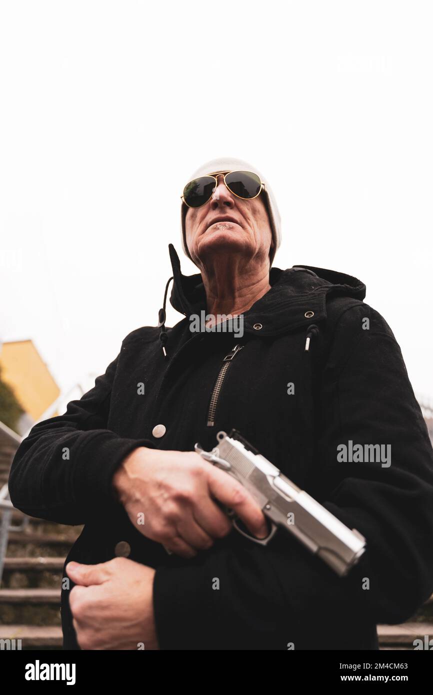 mature man rap singer posing in the street with a gun in his hand in the suburbs of a big city Stock Photo