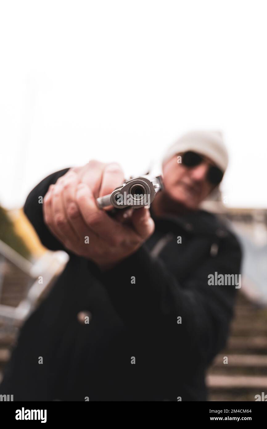 mature man rap singer posing in the street with a gun in his hand in the suburbs of a big city Stock Photo