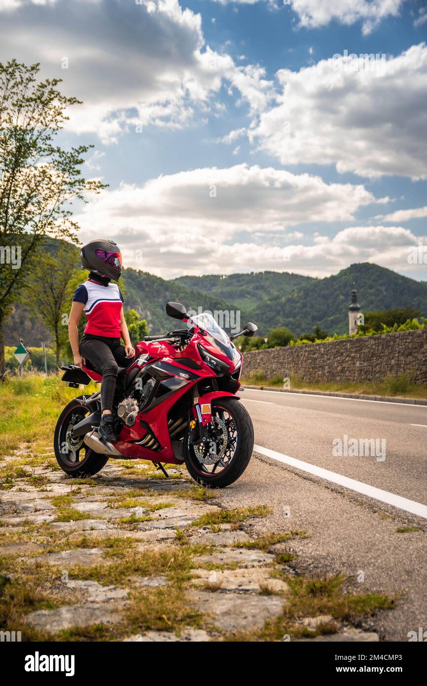 Cloudy day with an amazing young biker girl on her motorbike Stock Photo