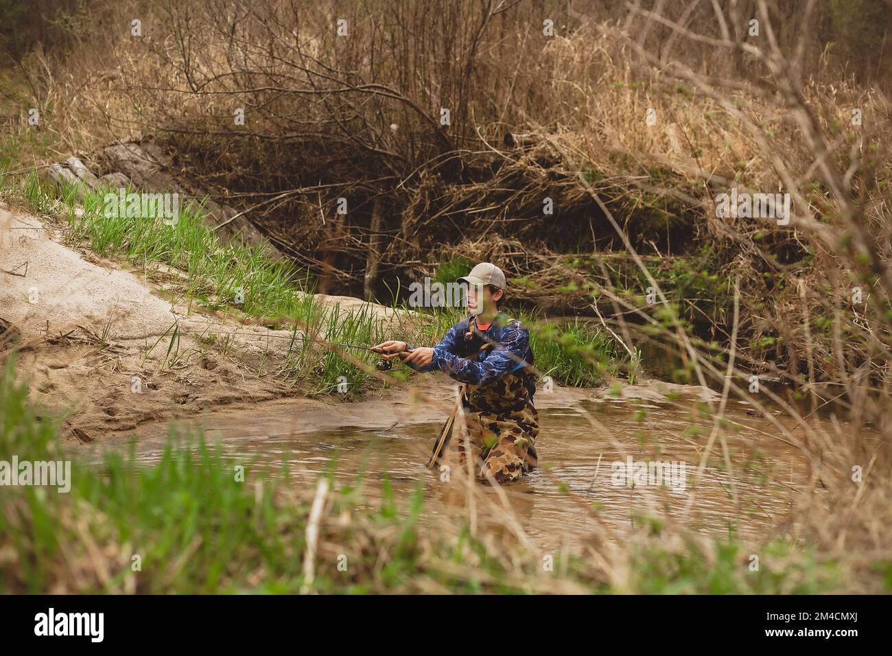 young man casting fishing pole in creek water Stock Photo