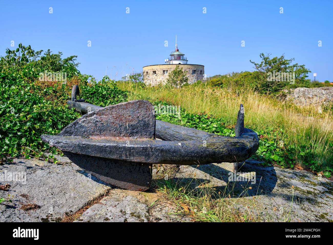 Out and about on the Ertholmen islands, rusty ship's anchor as well as the Great Tower (Store Tårn) and lighthouse,  Christiansö, Ertholmene, Denmark. Stock Photo