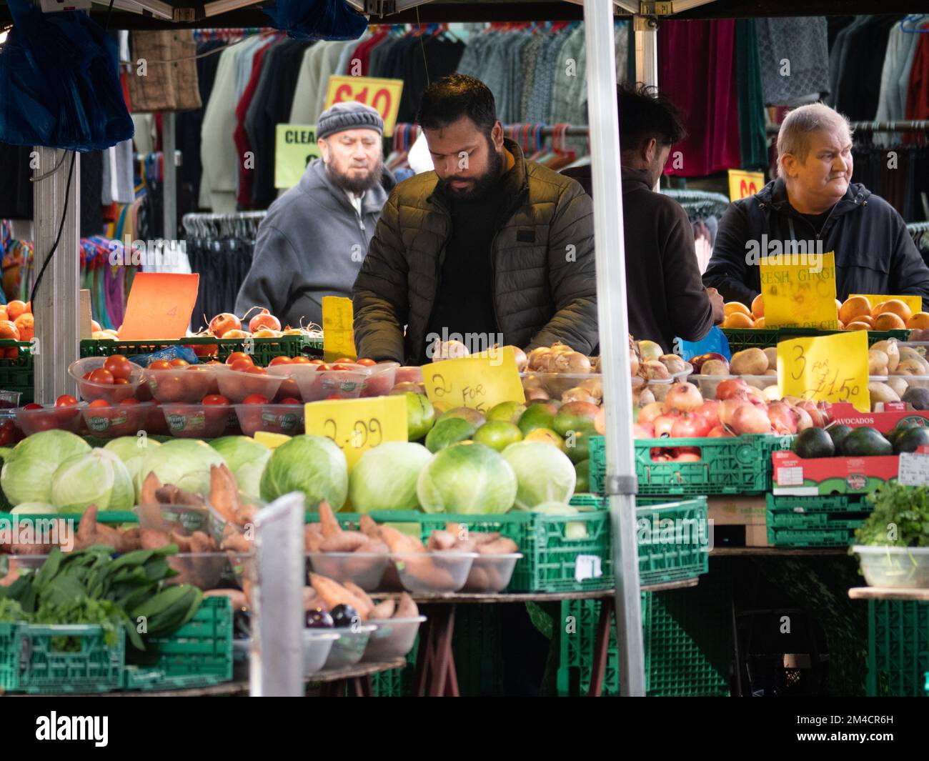 Greengrocer in Walthamstow market, London, UK, the longest outdoor market in Europe, with traders and market stall holders serving shoppers, with prices displayed in pounds sterling Stock Photo