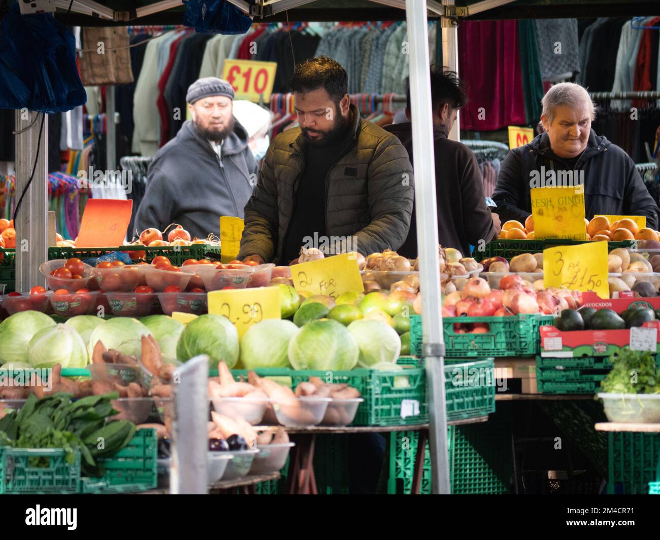 Greengrocer in Walthamstow market, London, UK, the longest outdoor market in Europe, with traders and market stall holders serving shoppers, with prices displayed in pounds sterling Stock Photo