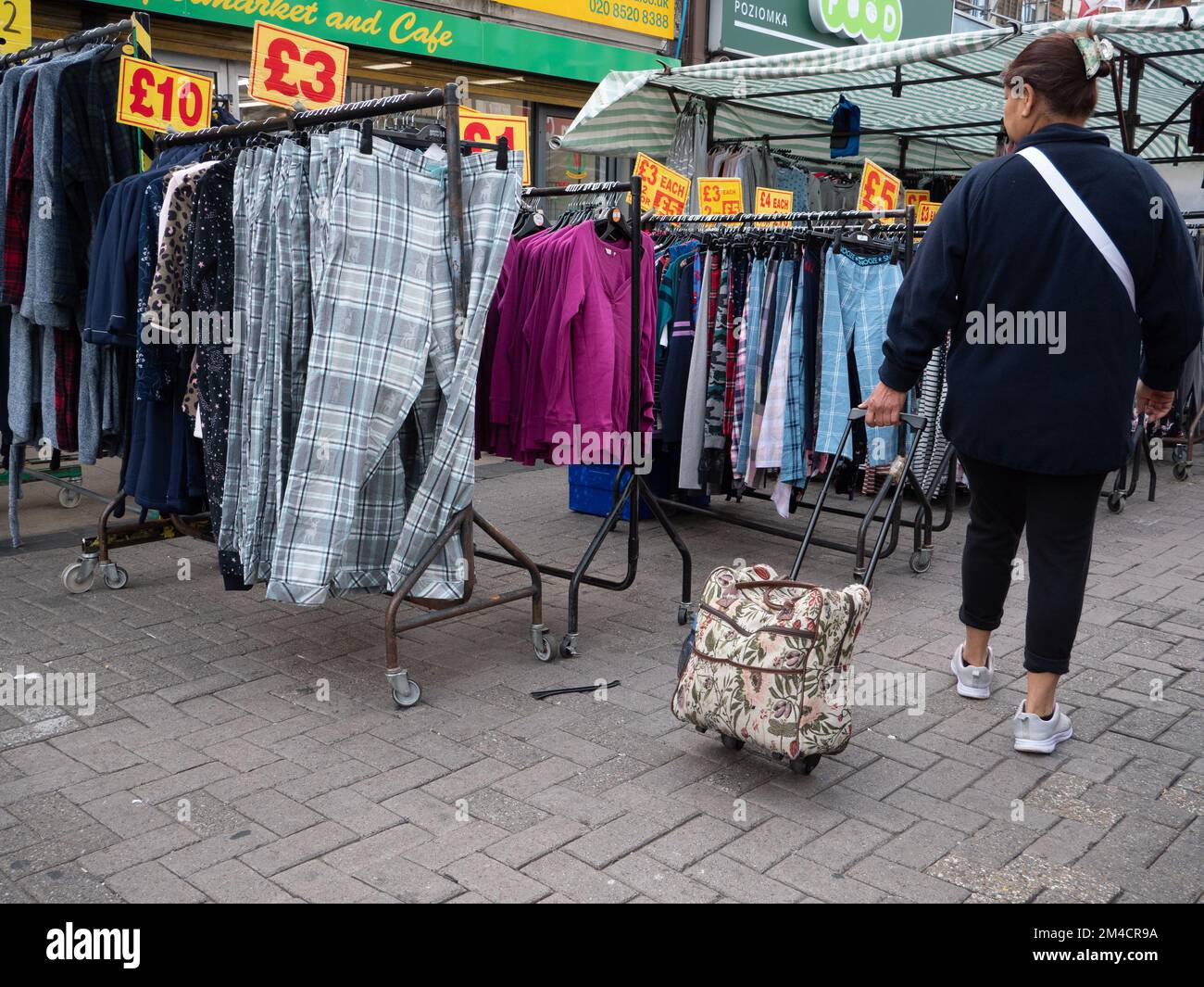 Shoppers looking at prices and goods in Walthamstow market, London, UK, the longest outdoor market in Europe. Traders and market stall holders serve shoppers, with prices displayed in pounds Stock Photo