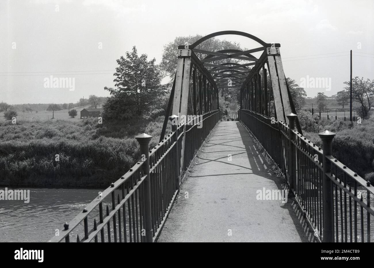 1950s, historical, Ford Bridge, Northenden Ford, Didsbury, Manchester, England, UK. The crossing is more commonly known as Simon Bridge, as its construction was funded by a local man Henry Simon. The iron footbridge over the River Mersey was built at the site of an old ford in 1901 to improve access to an area of land known as Poor's Field, as this land provided rents to the local church.  Historically the ford was a gateway into and out of the city of Manchester. Stock Photo