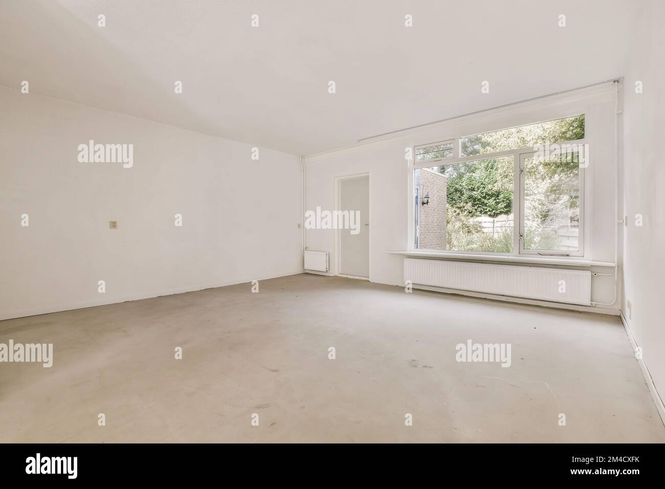 an empty room with white walls and no one person standing in the corner looking out at the view from the window Stock Photo
