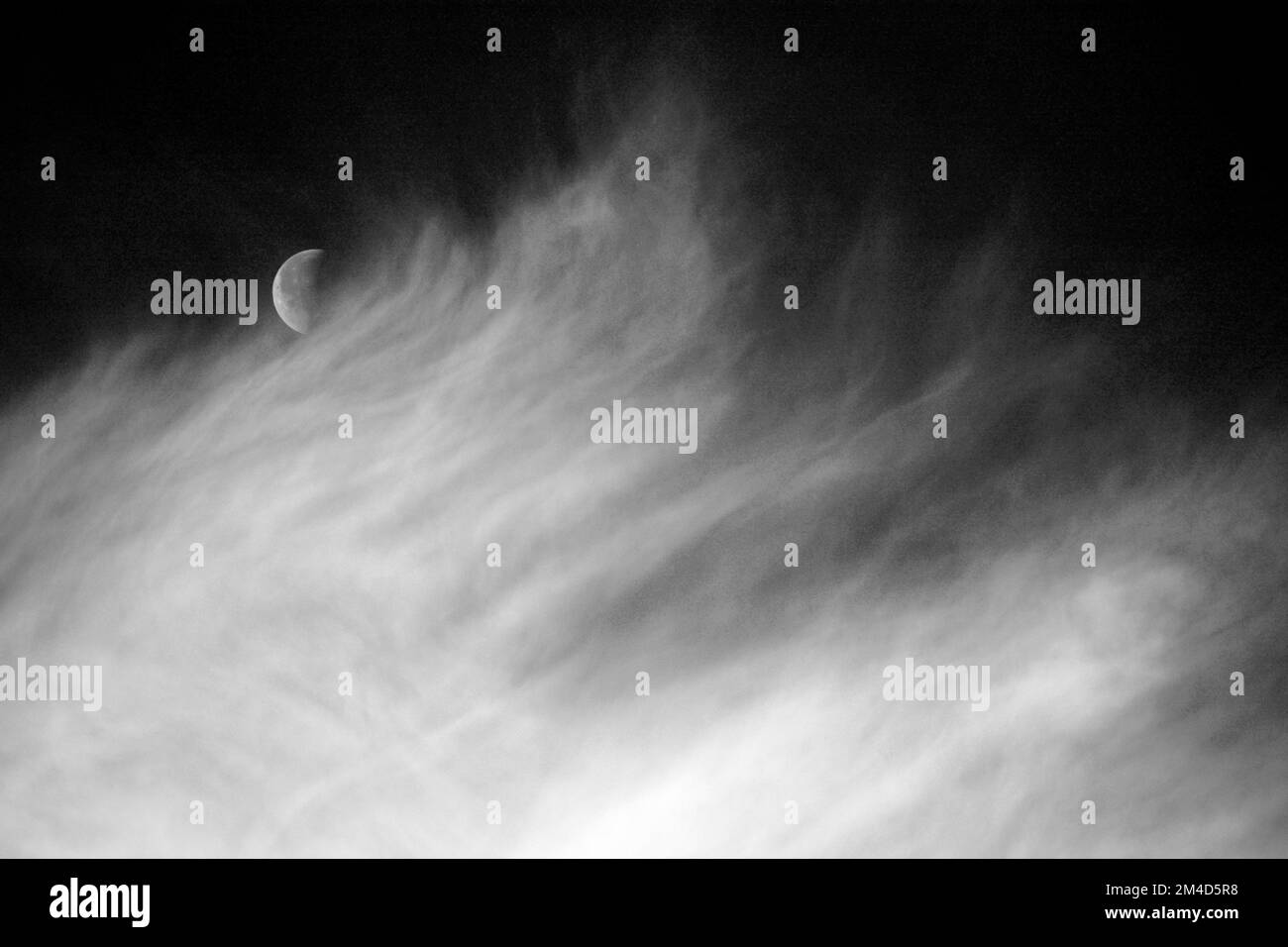 A half moon shares the sky with cirrus clouds over Santa Fe, New Mexico