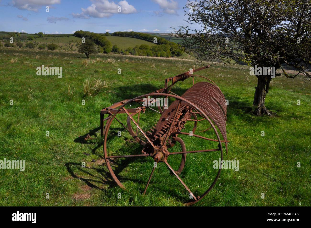 Hay rake retired to a field on Exmoor, converted from horse drawn to tractor powered. Exford, Somerset UK Stock Photo
