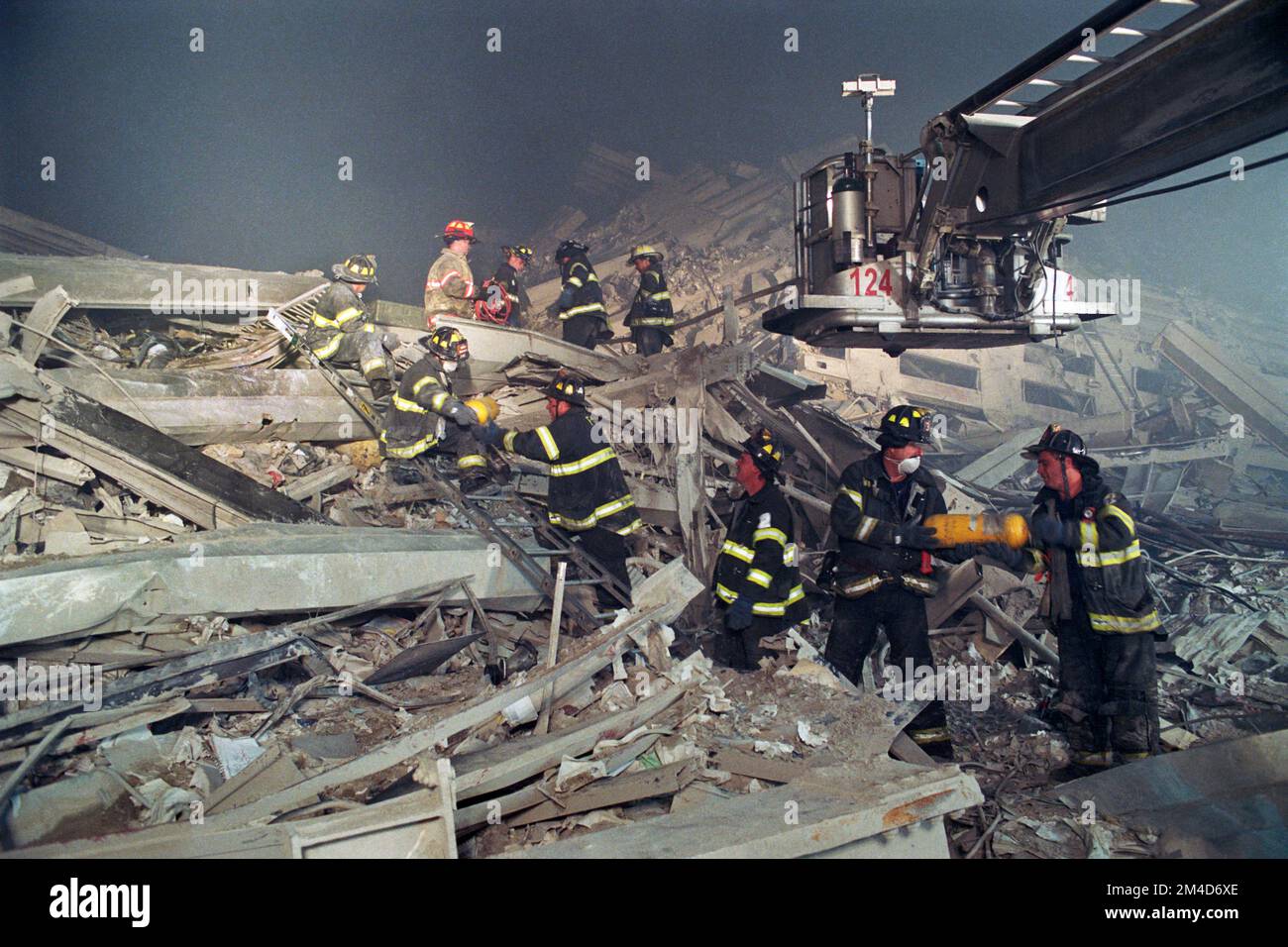 Members of FDNY Ladder Company 124 are assisted by other firefighters as they remove tools and equipment from 'the pile' in the early morning hours of Stock Photo