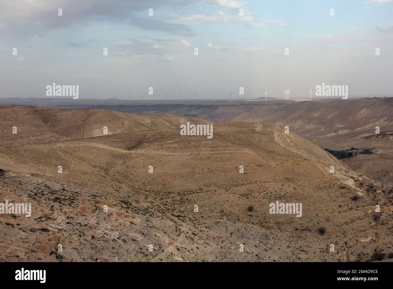 Desert landscape view of sunny rocky cliff with wind turbines in view taken from Shobak Castle, Jordan Stock Photo