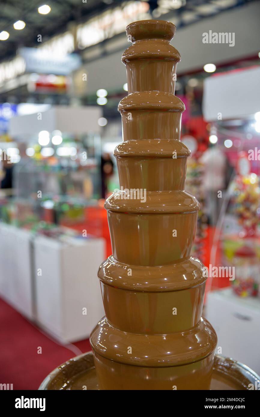 chocolate fountain hot liquid flowing down tower pyramid closeup Stock Photo