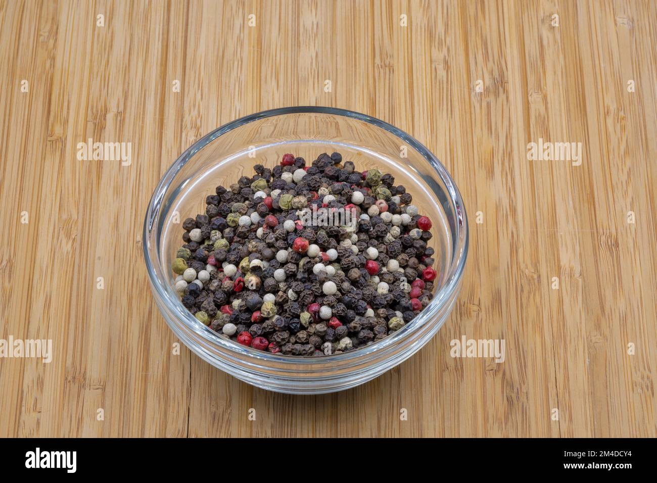 A mixture of peppers in a glass bowl closeup on wooden background Stock Photo