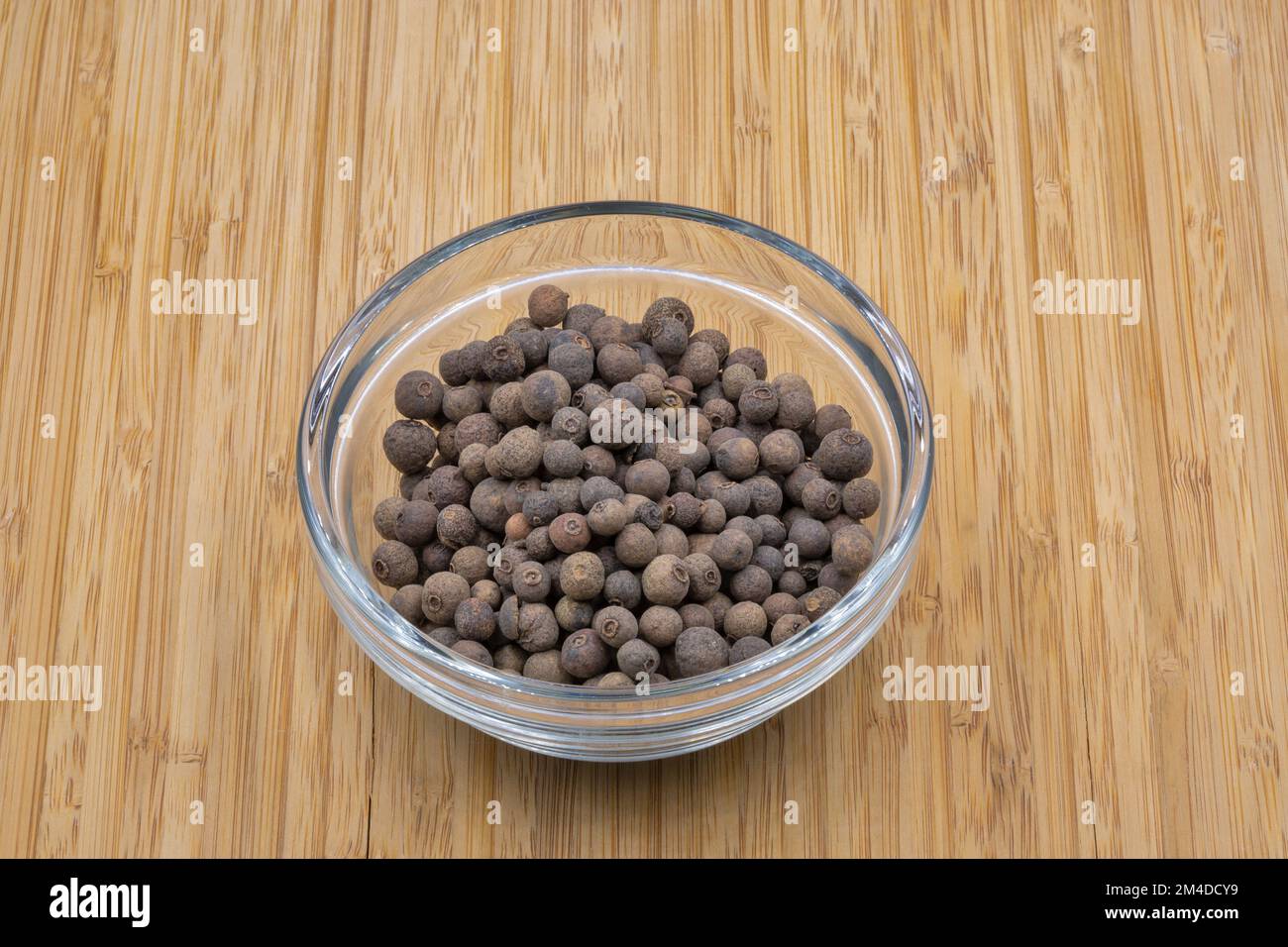 Allspice pepper in a glass bowl closeup on wooden background Stock Photo