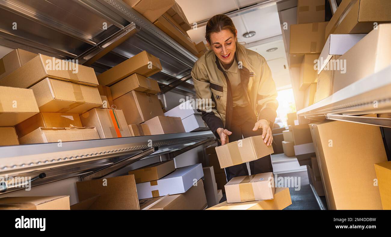 female delivery agent sorting in her van parcels to deliver it to a customer. Courier Delivery concept image Stock Photo