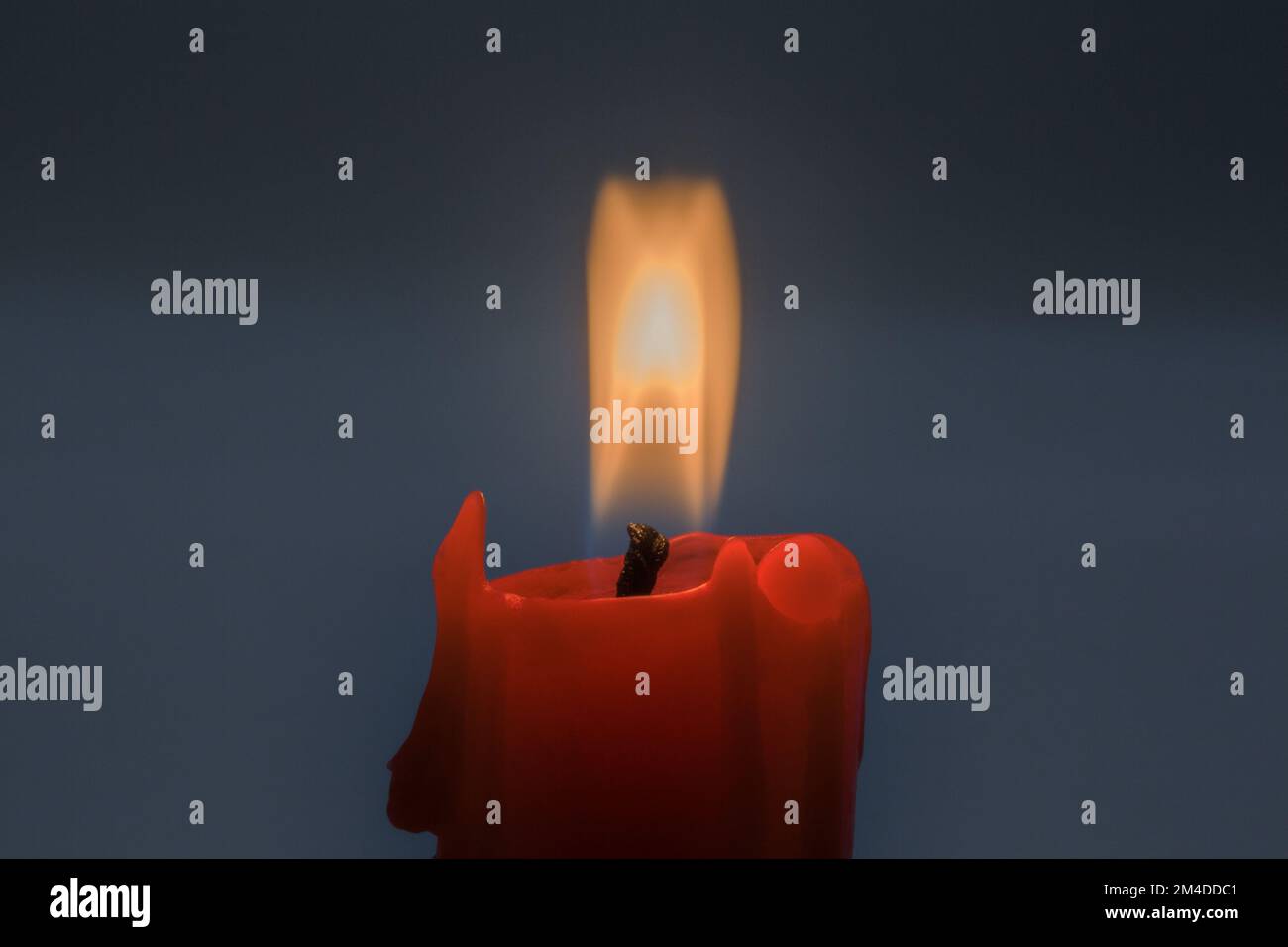 burning small red candle stub closeup on dark background Stock Photo