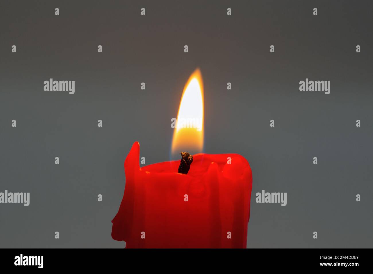 burning small red candle stub closeup on dark background Stock Photo