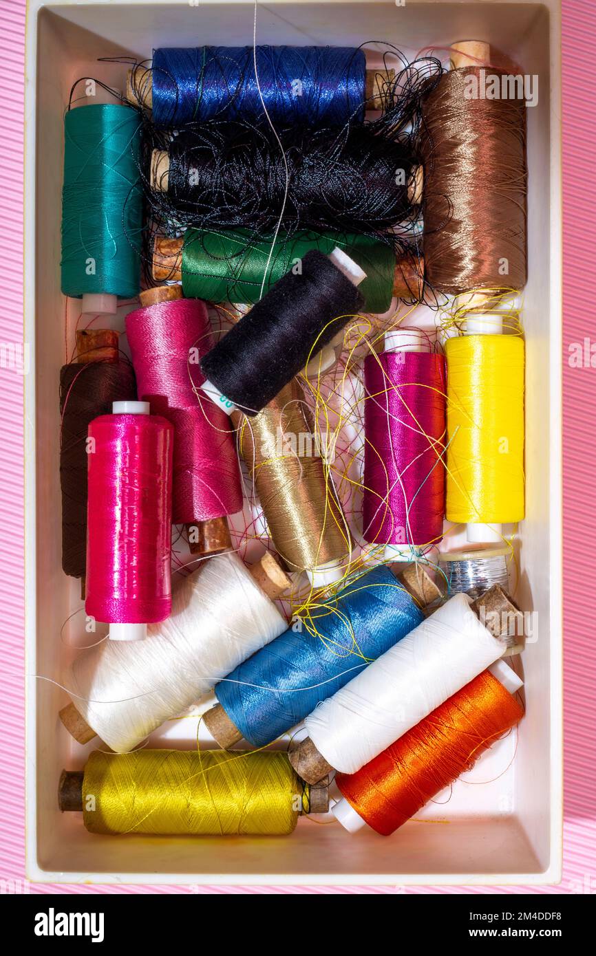 A box with multi colored coins of different threads on a colored ...