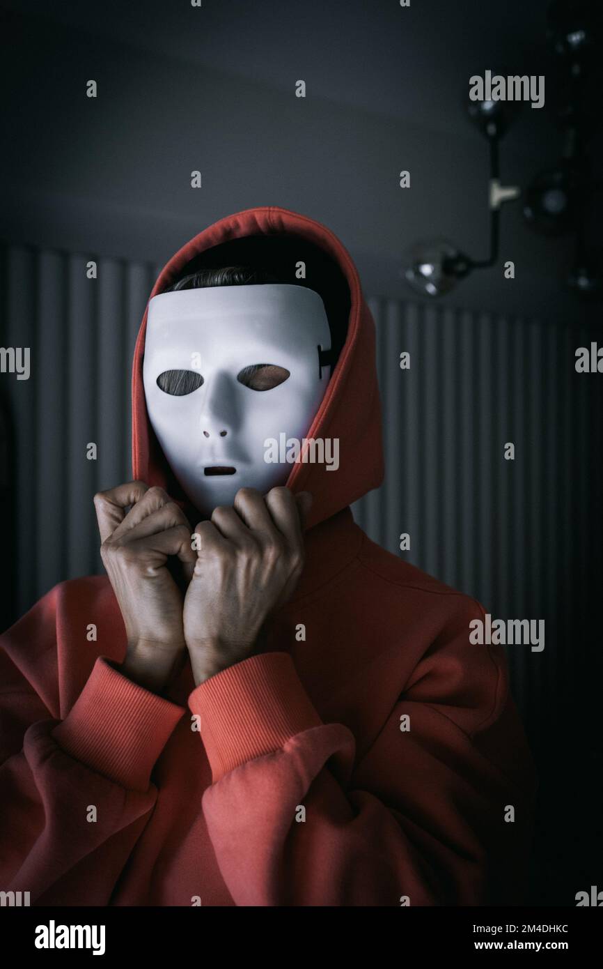 Portrait of woman in white theater mask and hood on black background. Concept of mental disorders, hypocrisy. High quality photo Stock Photo