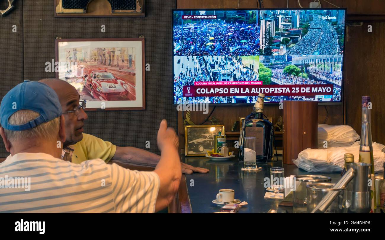 Men in a bar in Buenos Aires, Argentina watch TV coverage of the open top bus carrying Argentina's FIFA World Cup winning team into the city - before Stock Photo