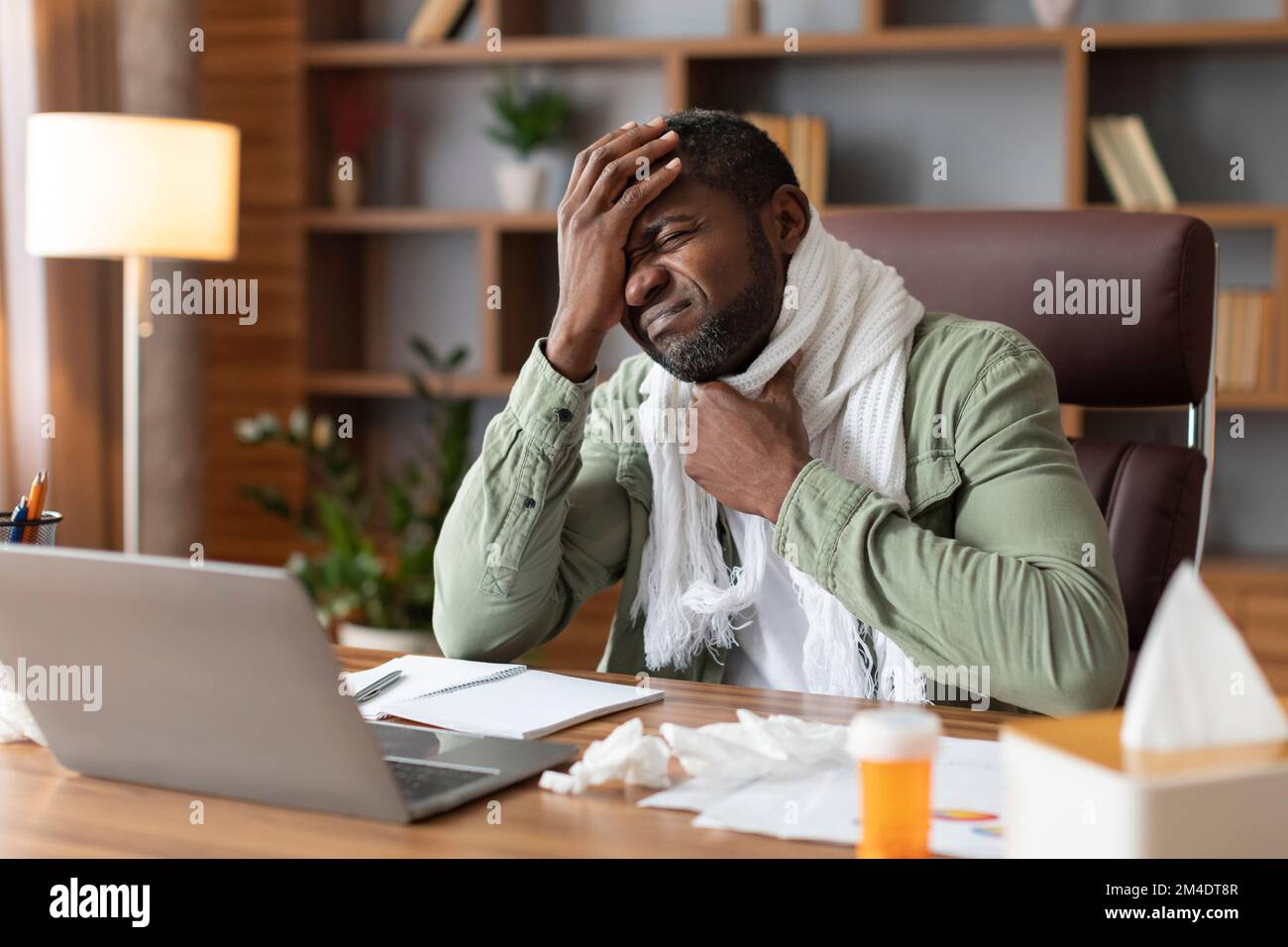 Despaired unhappy middle aged black businessman in scarf suffer from sore throat and high temperature Stock Photo