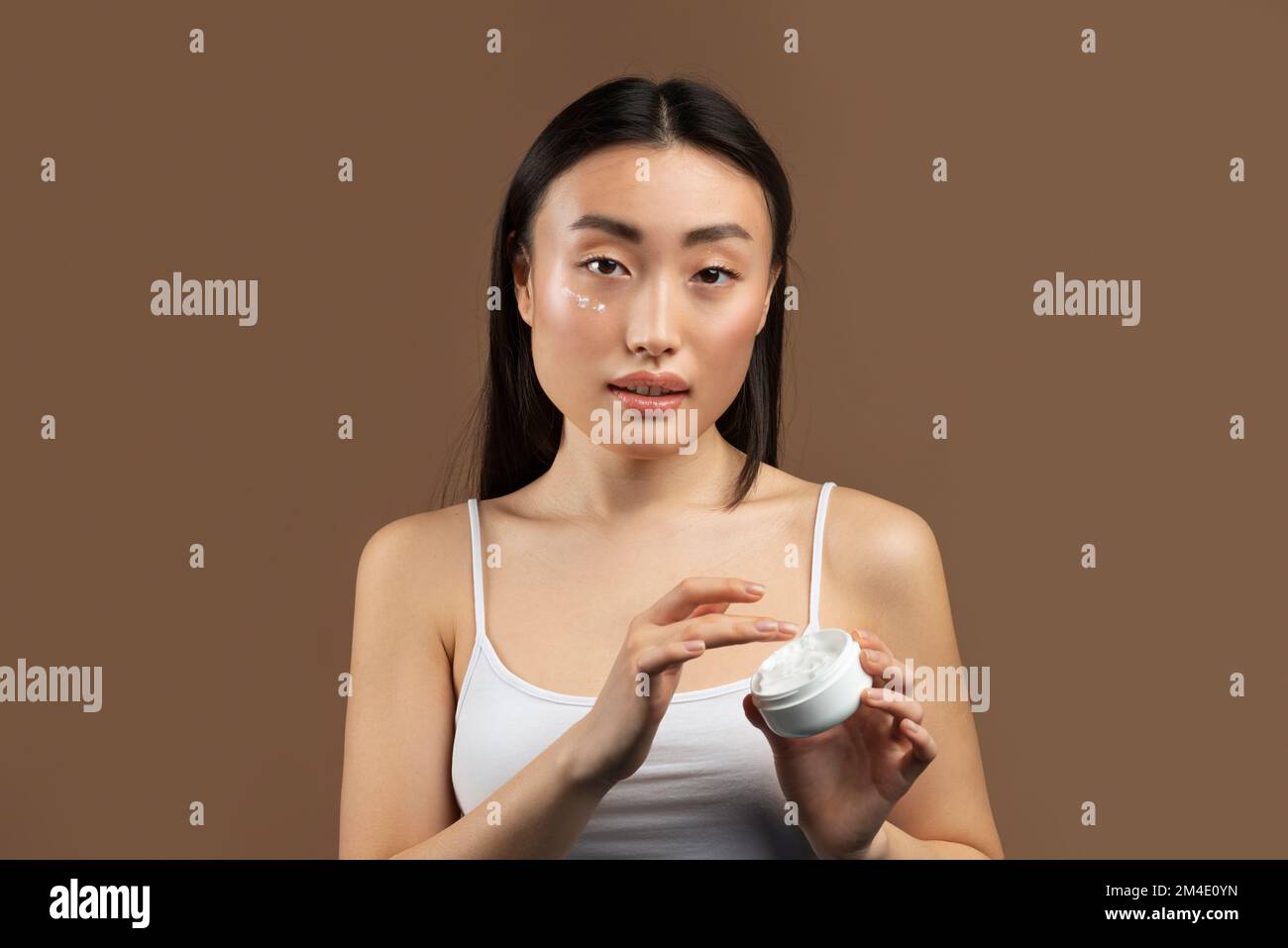 Skincare cosmetics concept. Korean lady trying new moisturising product