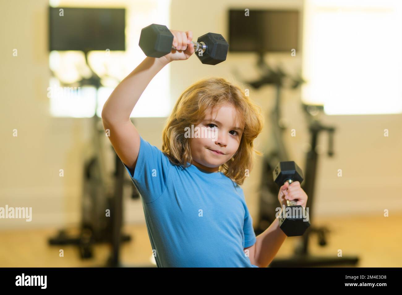 Child workout kid in gym. Kid sport. Child exercising with dumbbells. Sporty child with dumbbell. Stock Photo