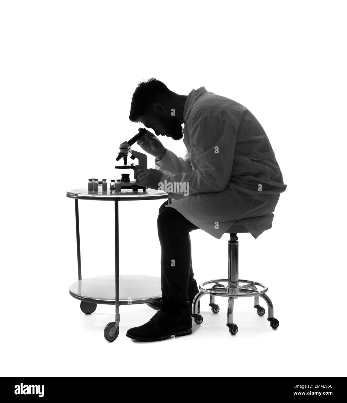 Silhouette of male scientist working with microscope on white background Stock Photo