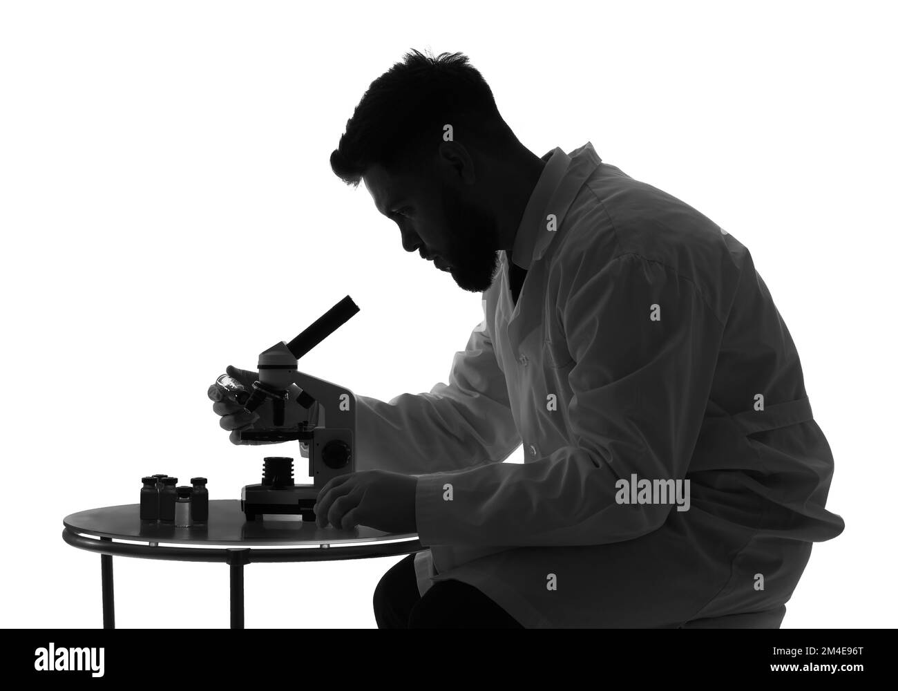 Silhouette of male scientist working with microscope on white background Stock Photo
