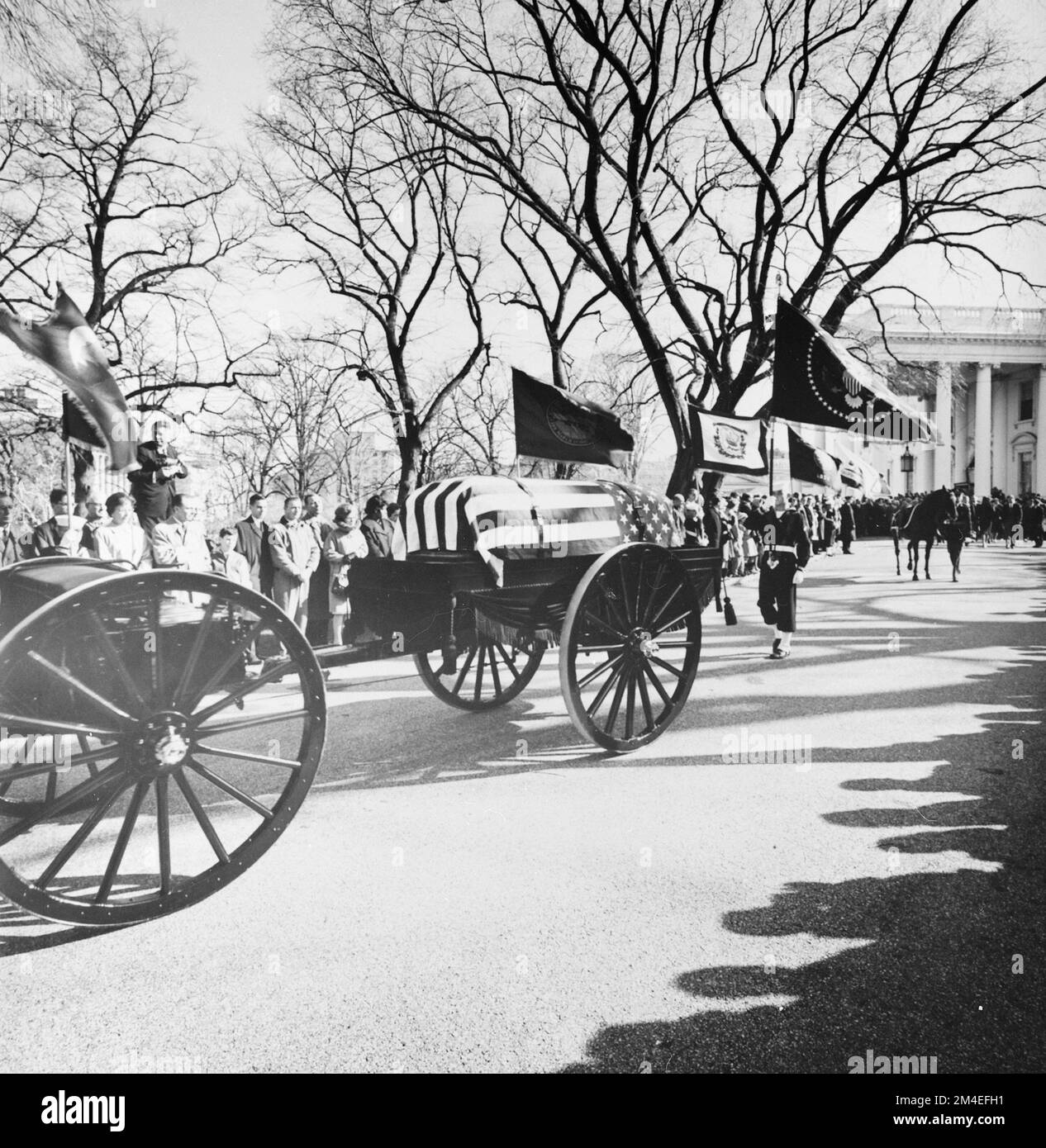 A limbers and caissons bearing the casket of U.S President John F. Kennedy seen moving down the White House drive on the way to St. Matthew's Cathedral on November 25, 1963. A color guard holding the presidential colors, the flag of the President of the United States, and the riderless horse 'Black Jack', follow behind. Stock Photo