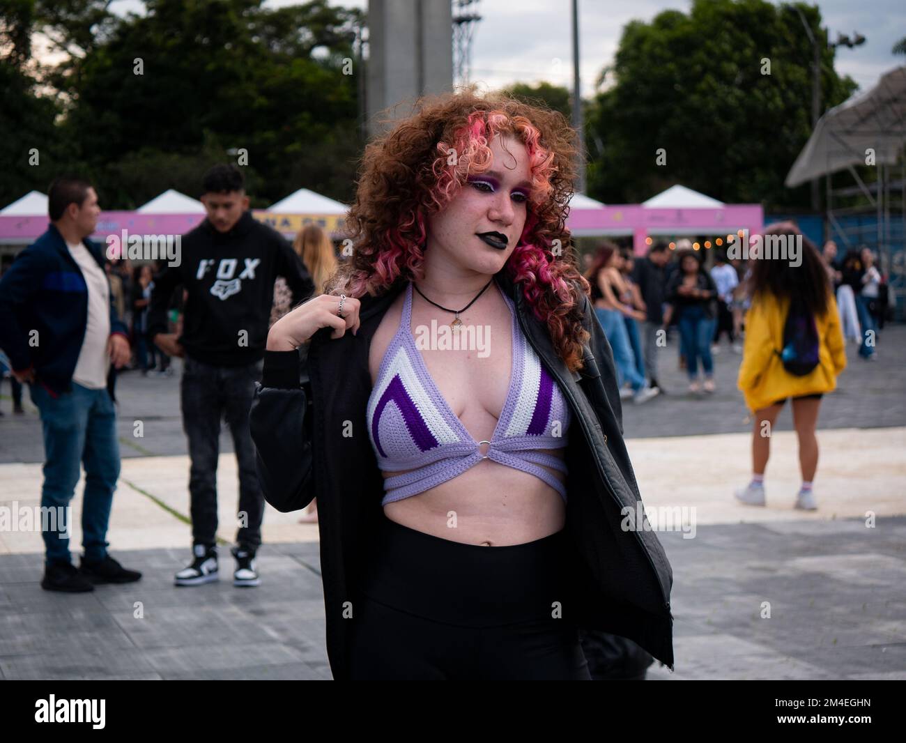 Medellin, Antioquia, Colombia - November 14 2022: A Colombian Woman with Curly Pink Hair and Black Lips is Posing in the Middle of a Crowd Stock Photo