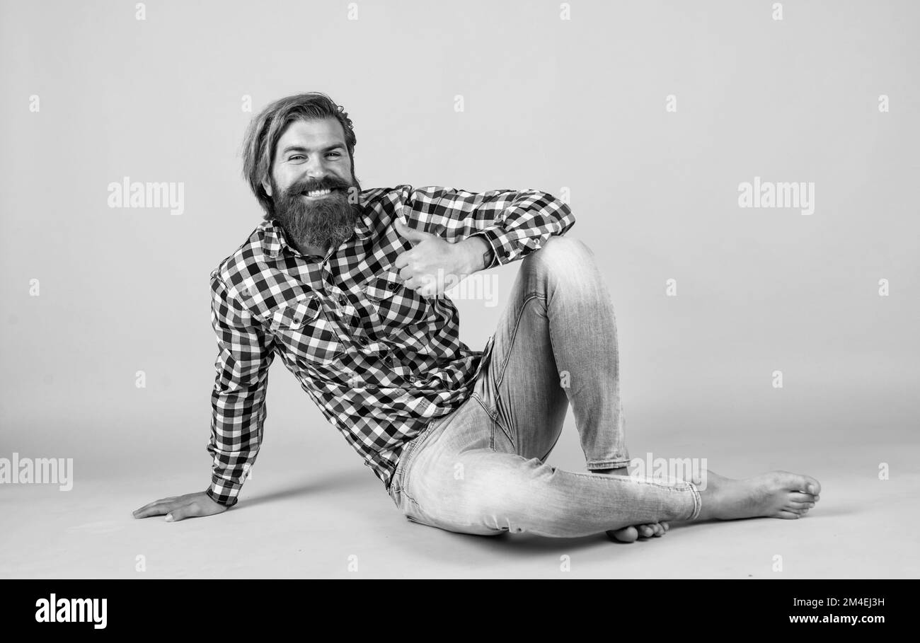 carefree and barefoot. male wearing checkered shirt. casual male fashion. best barbershop. Handsome bearded man in casual clothes smiling. Cheerful Stock Photo