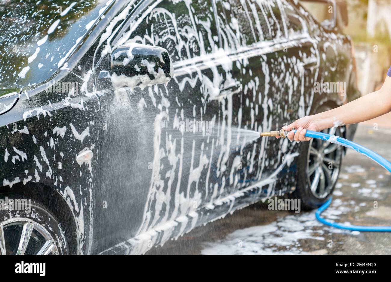 Spraying foam to a black car with high pressure foam gun car wash at