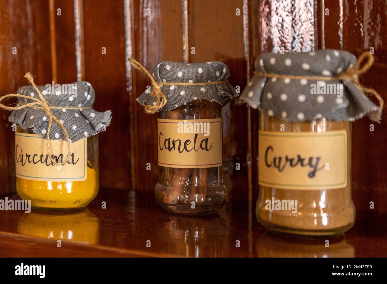 A closeup shot of jars with spices, with dotted cloths on lids, with names of spices written on