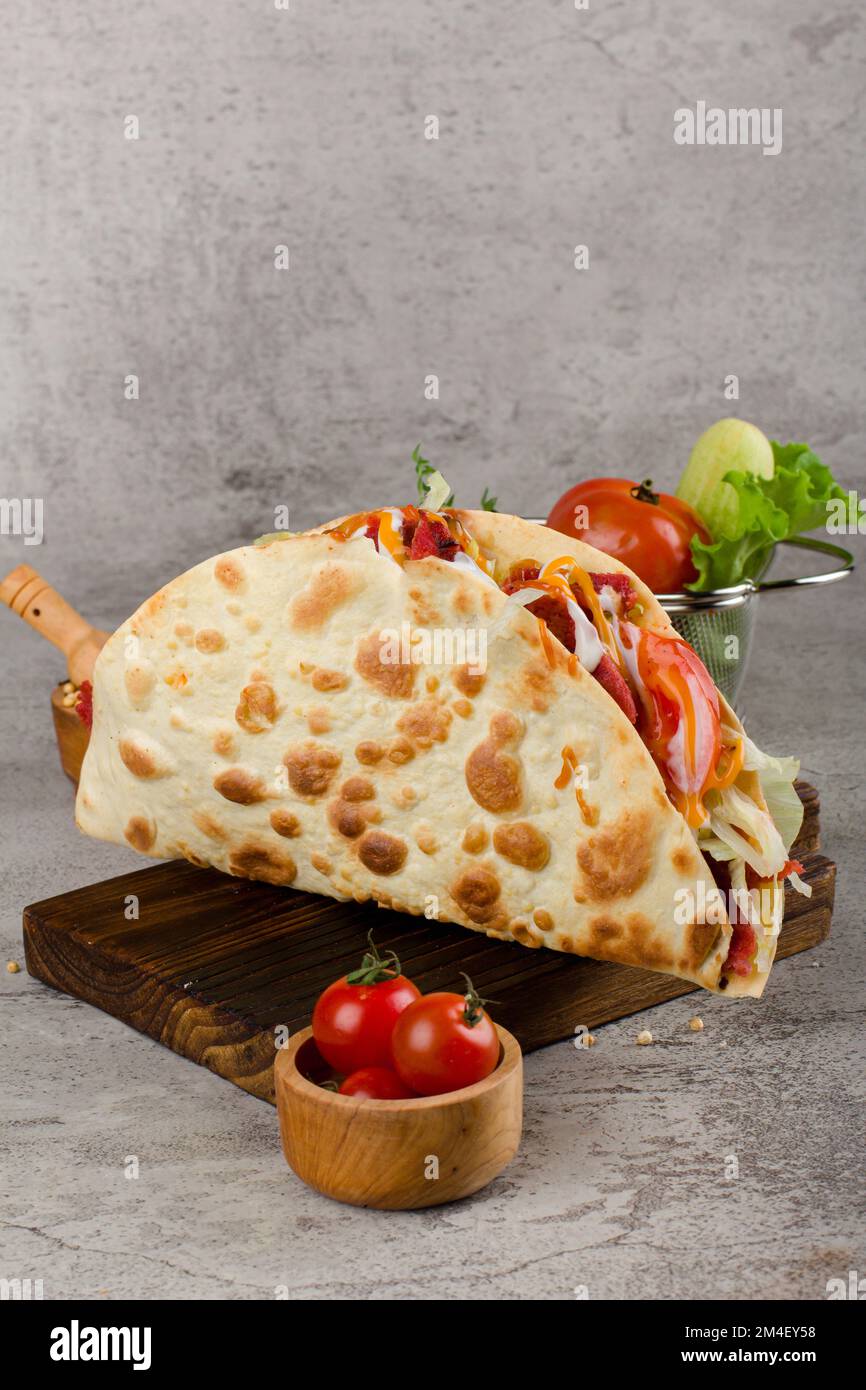 Mexican Tacos with beef, lettuce, tomato and Cheese sauce on wooden rustic cutting board Stock Photo