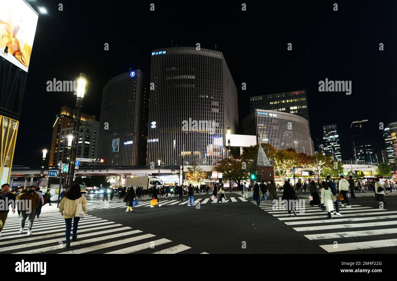 Pedestrians crossing the road in Ginza with Yurakucho business district in front of them. Tokyo, Japan. Stock Photo