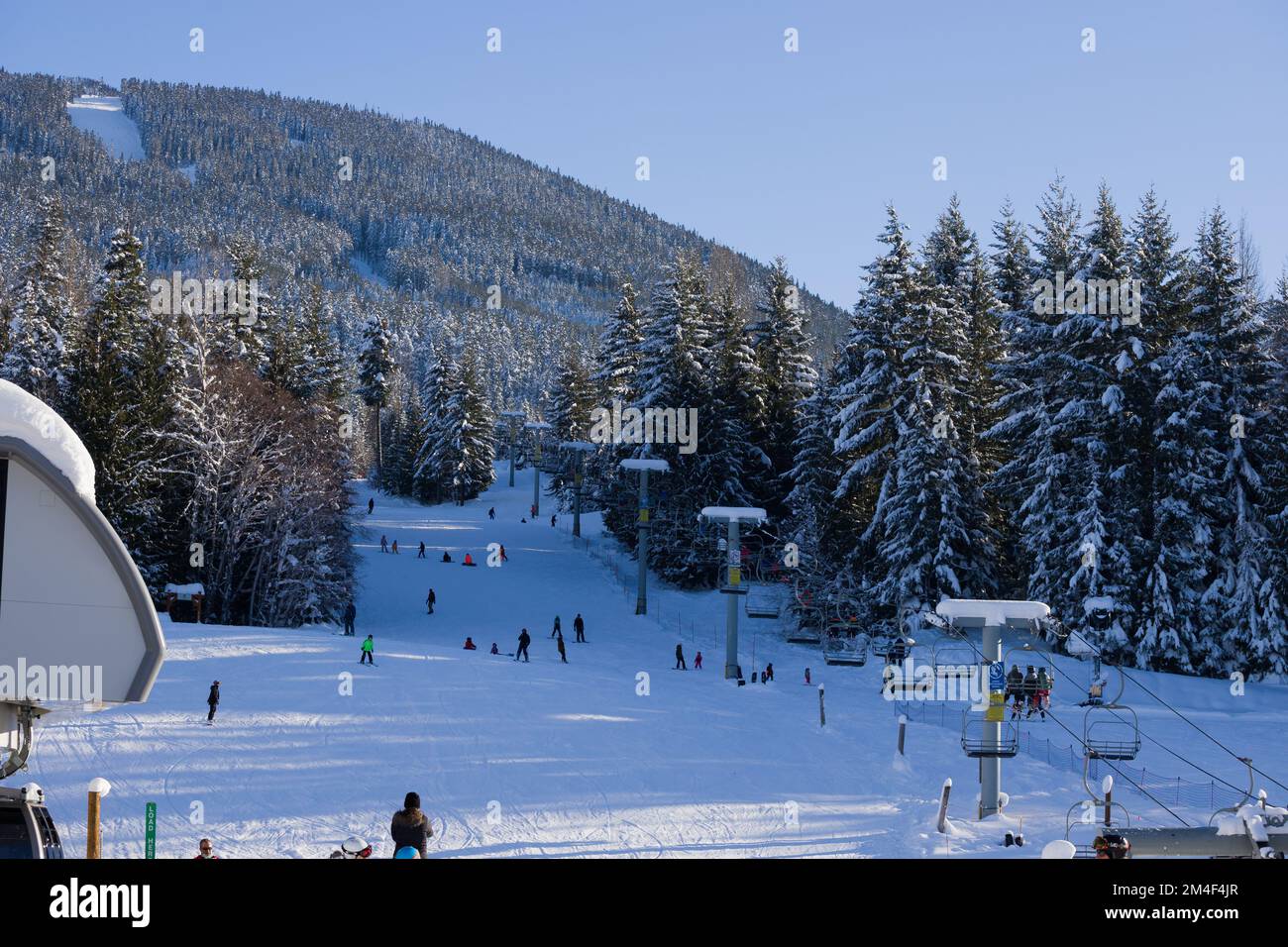 Snow covered mountains panorama snowboarders and skiers ride on slopes and ski lifts. Ski
