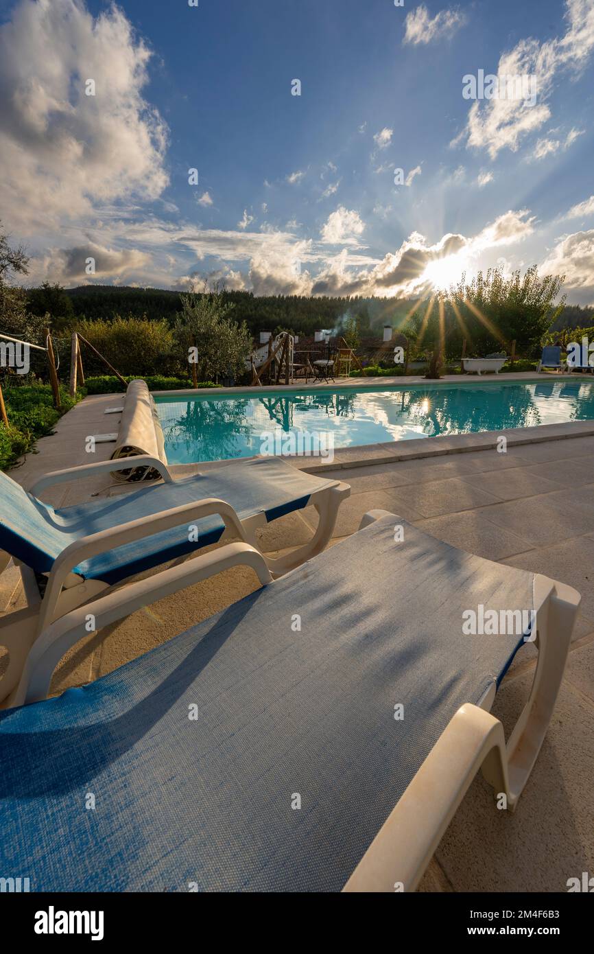 Reclining sun loungers next to an outdoor swimming pool Stock Photo