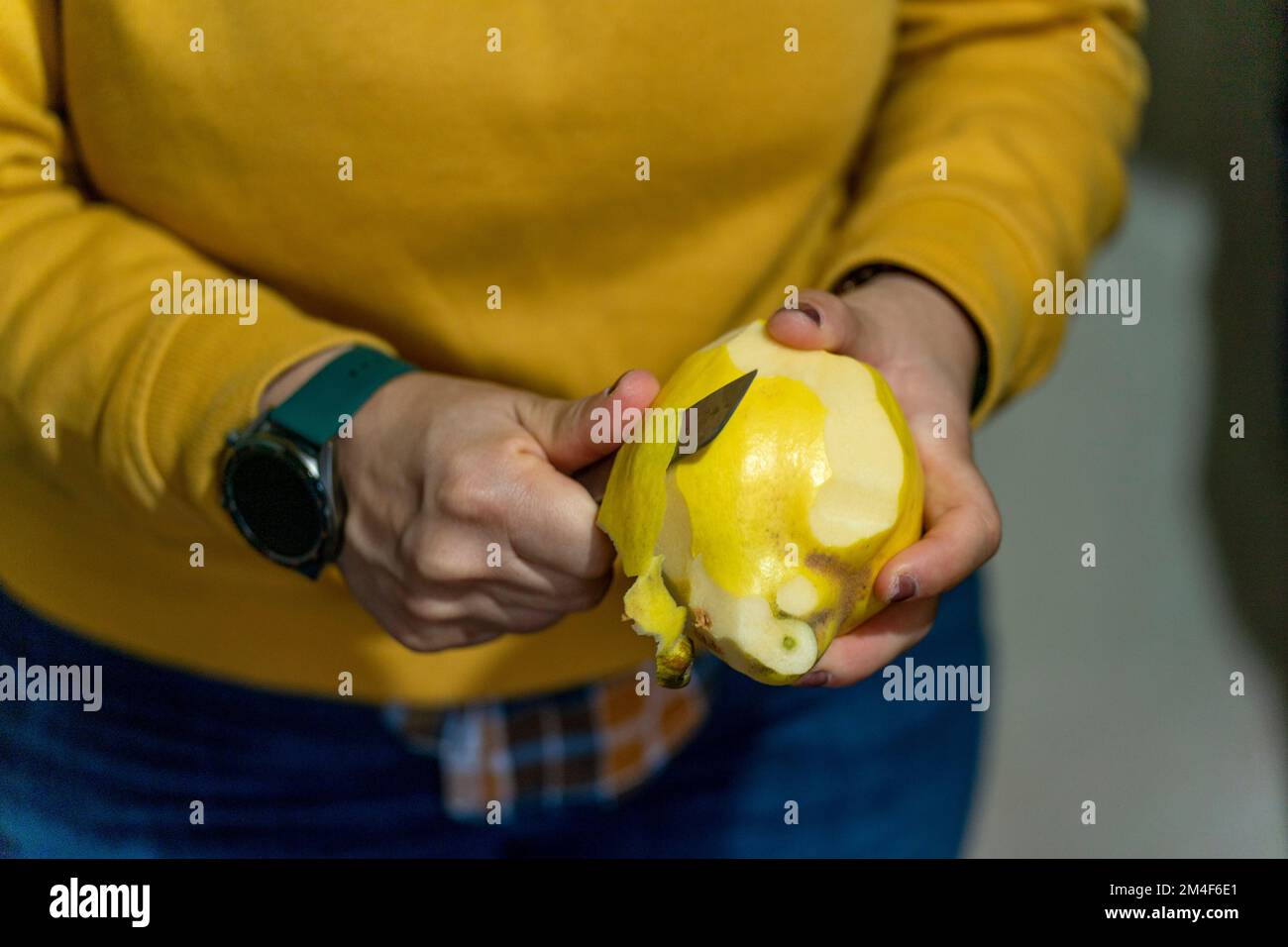 Close up of a person peeling fruit with a small sharp knife Stock Photo