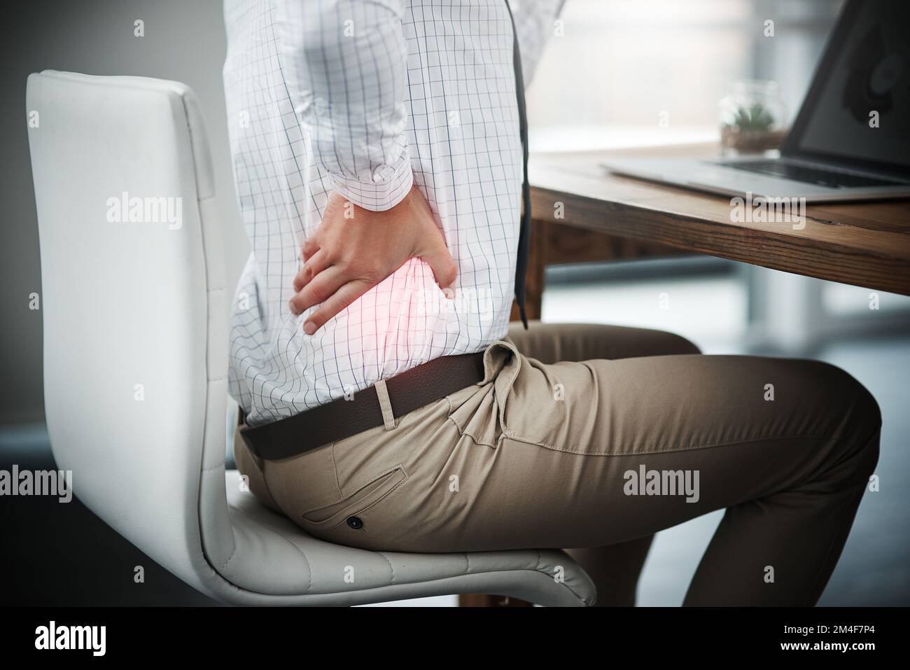 Sitting too long can bring unbearable tension to the back. Closeup shot of an unrecognizable businessman suffering with back pain while working in an Stock Photo
