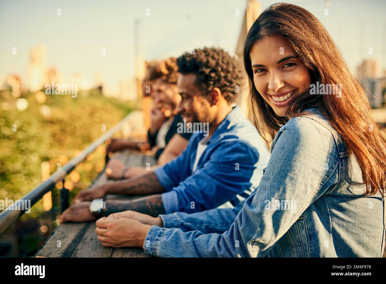 Looking at the awesome scenery together. friends standing in a row spending the day outside on a rooftop. Stock Photo