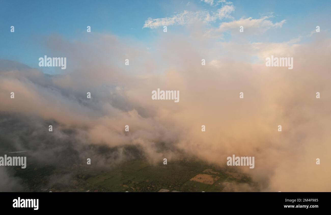 Fluffy clouds cover green landscape aerial drone view Stock Photo