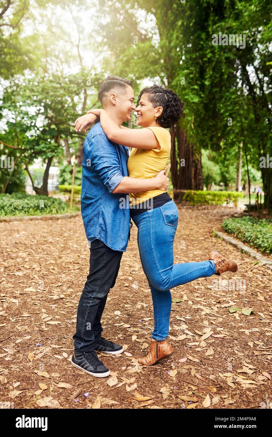 Love conquers all. Full length shot of an affectionate young couple embracing while standing outside in the park. Stock Photo