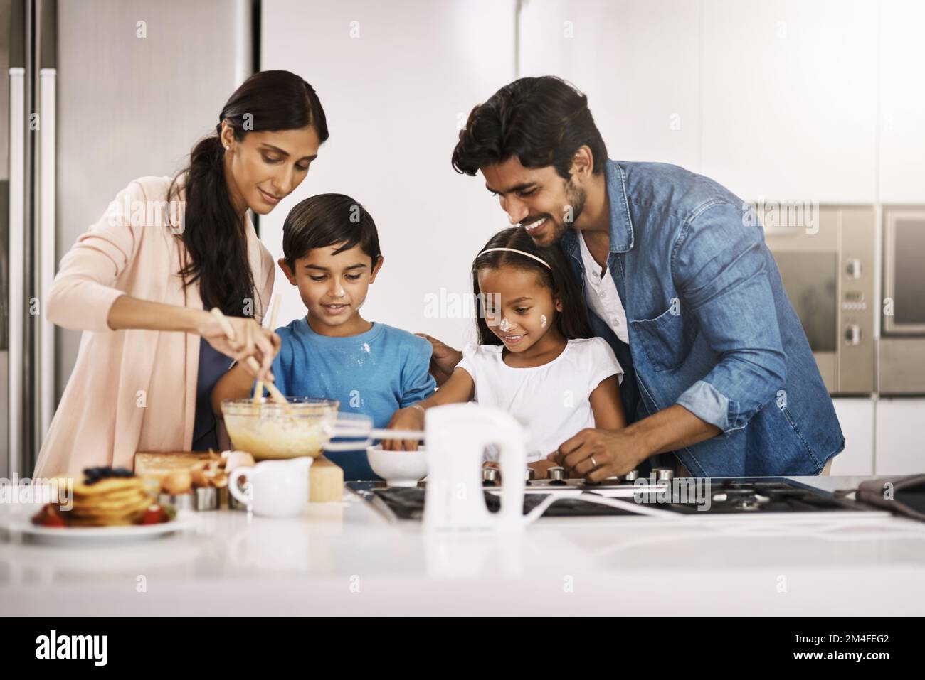 Breakfast always tastes better when you make it yourself. an affectionate young family cooking breakfast in their kitchen at home. Stock Photo