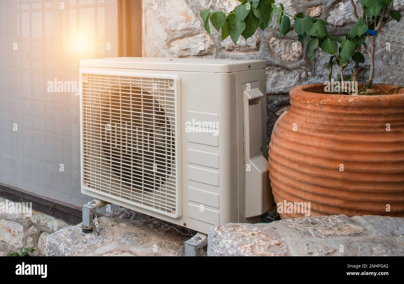 Air heat pump outdoor unit against wall of Greek house. Stock Photo