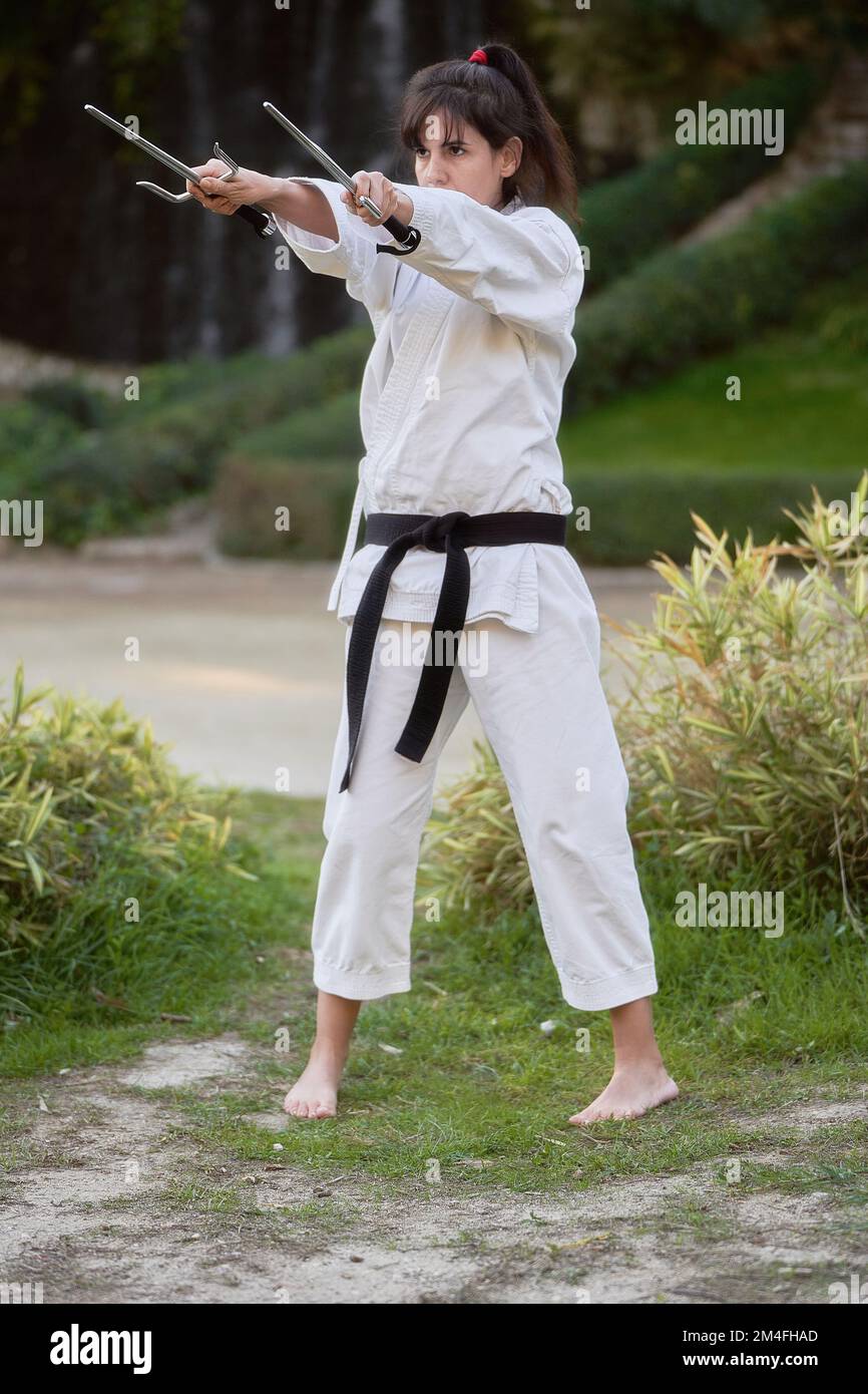 Female karate fighter with black belt practicing karate outdoors in the