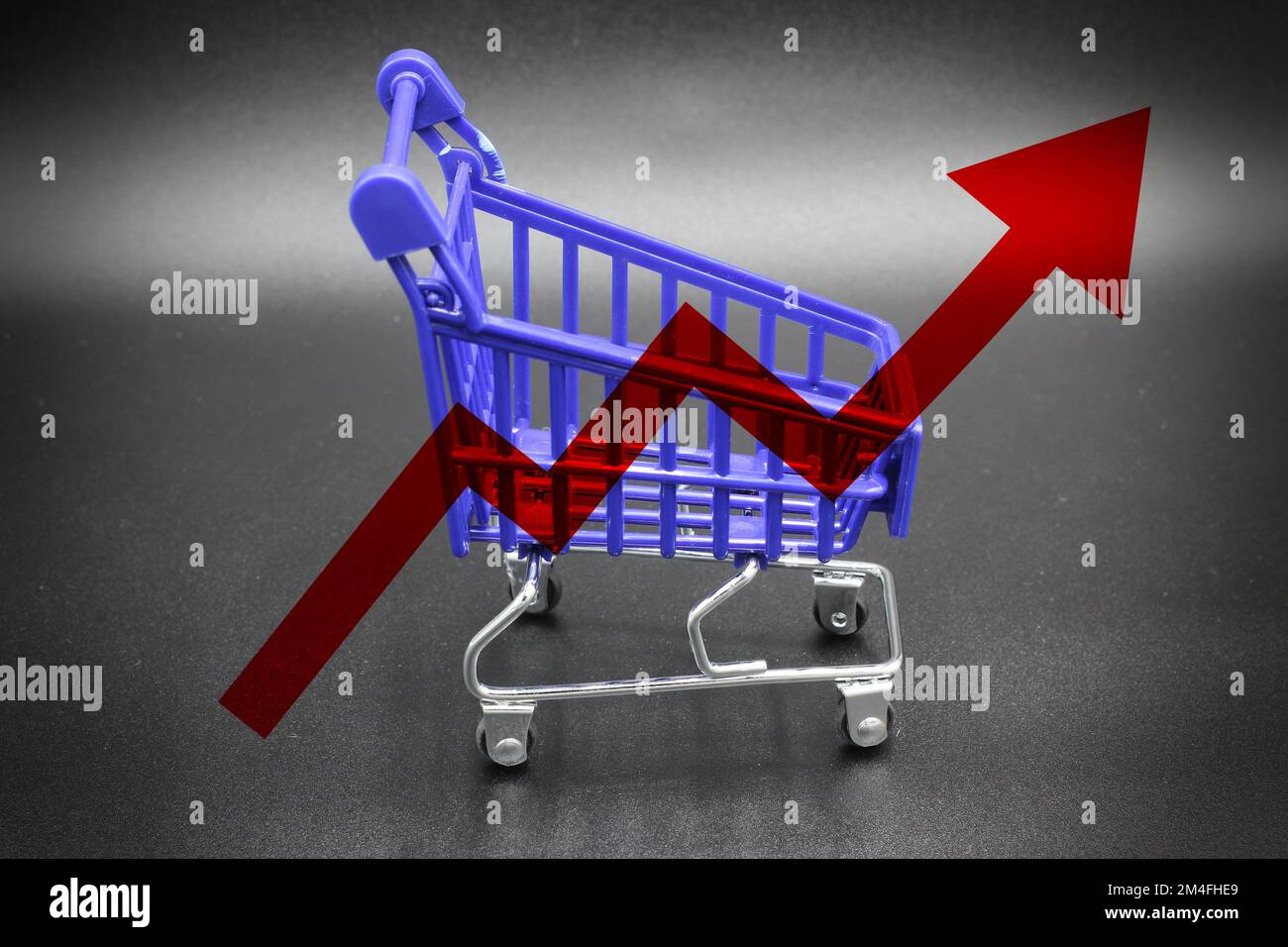 Isolated shopping cart with a red graph arrow concept of rising food cost and grocery prices