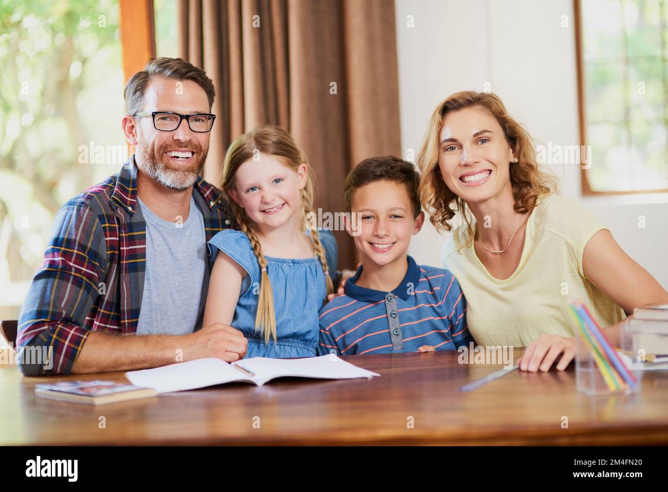 This is our family bonding educational time. two parents helping their adorable children with schoolwork at home. Stock Photo