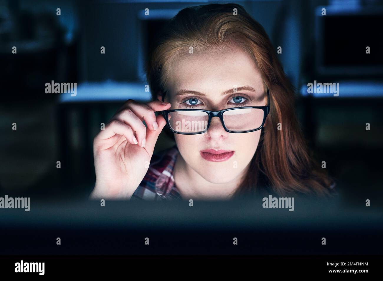 Shell be watching you. Portrait of a focused young female programmer working on a computer in the office at work during the night. Stock Photo