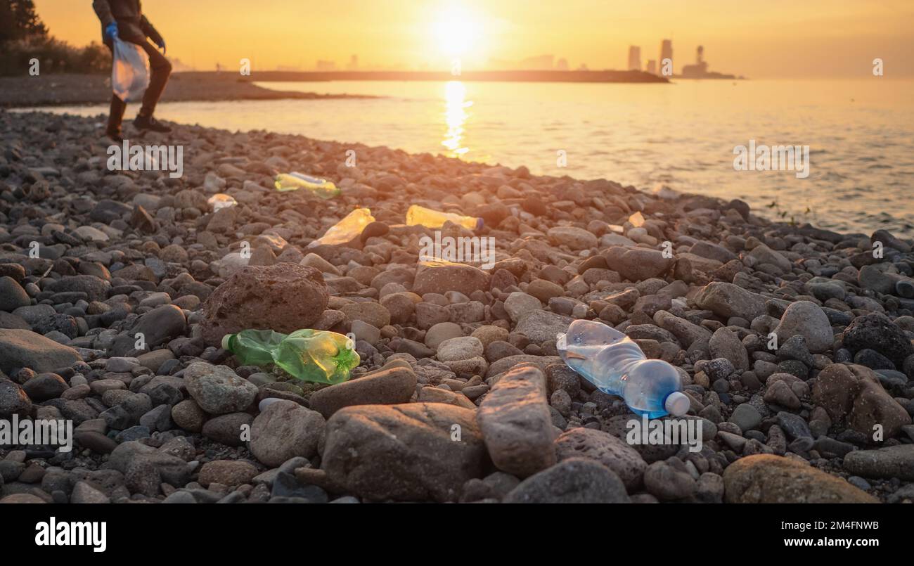 Process of cleaning stone beach from plastic waste. Man picks up